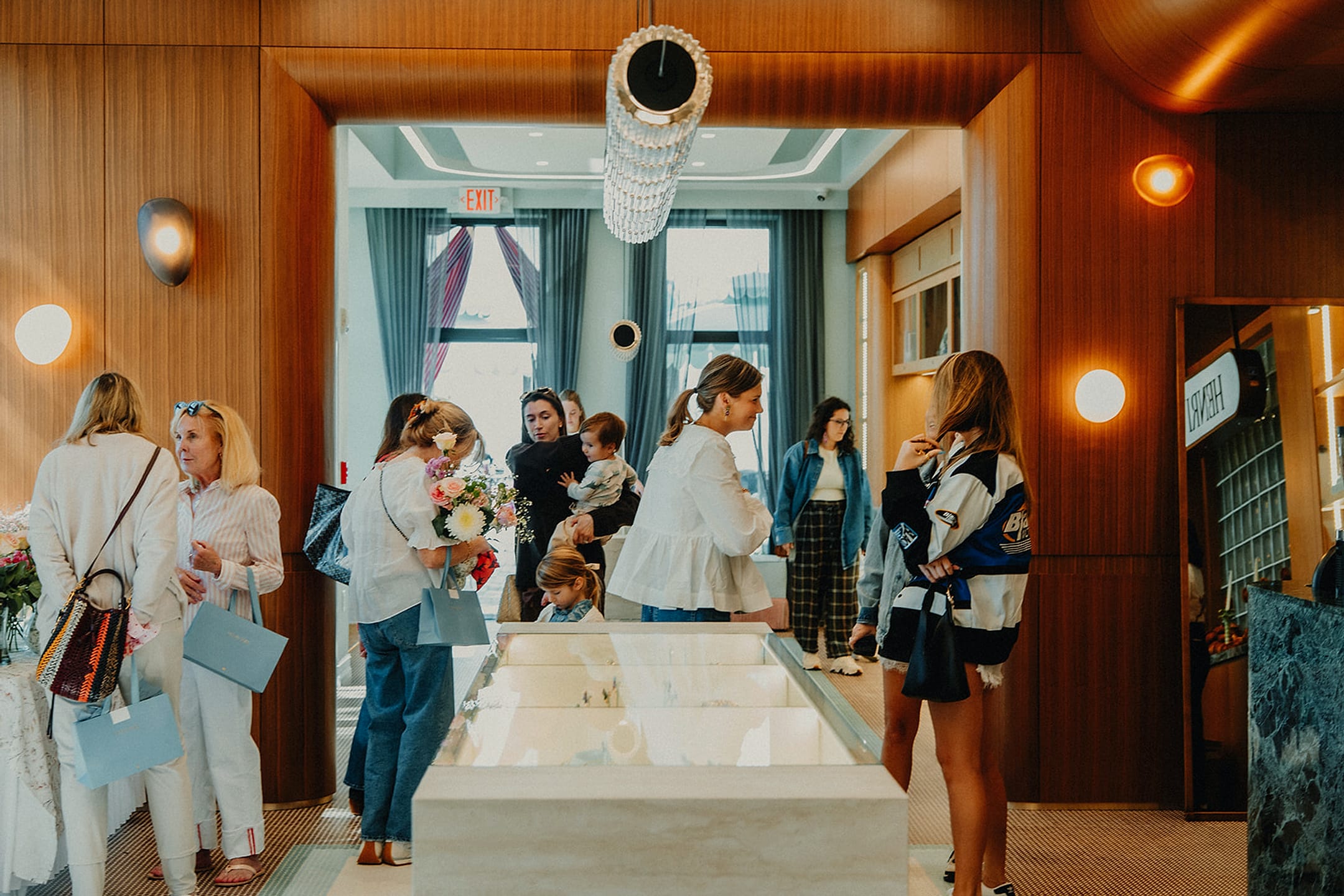 Guests gathered at a morning event catered by Wolfmoon, talking, holding flowers, the host laughing in the middle of the room