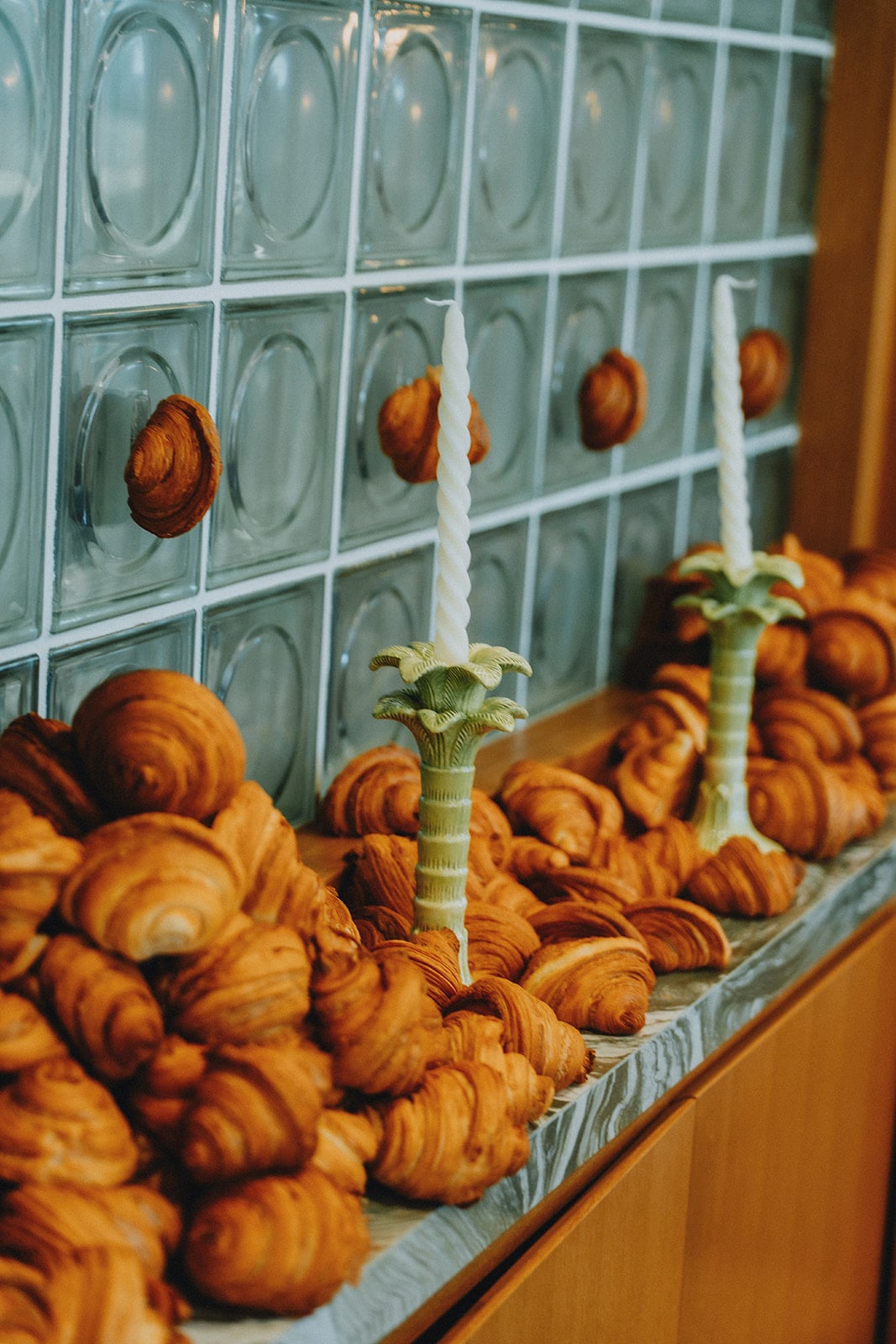 Croissants piled along a counter between candles at a catered event